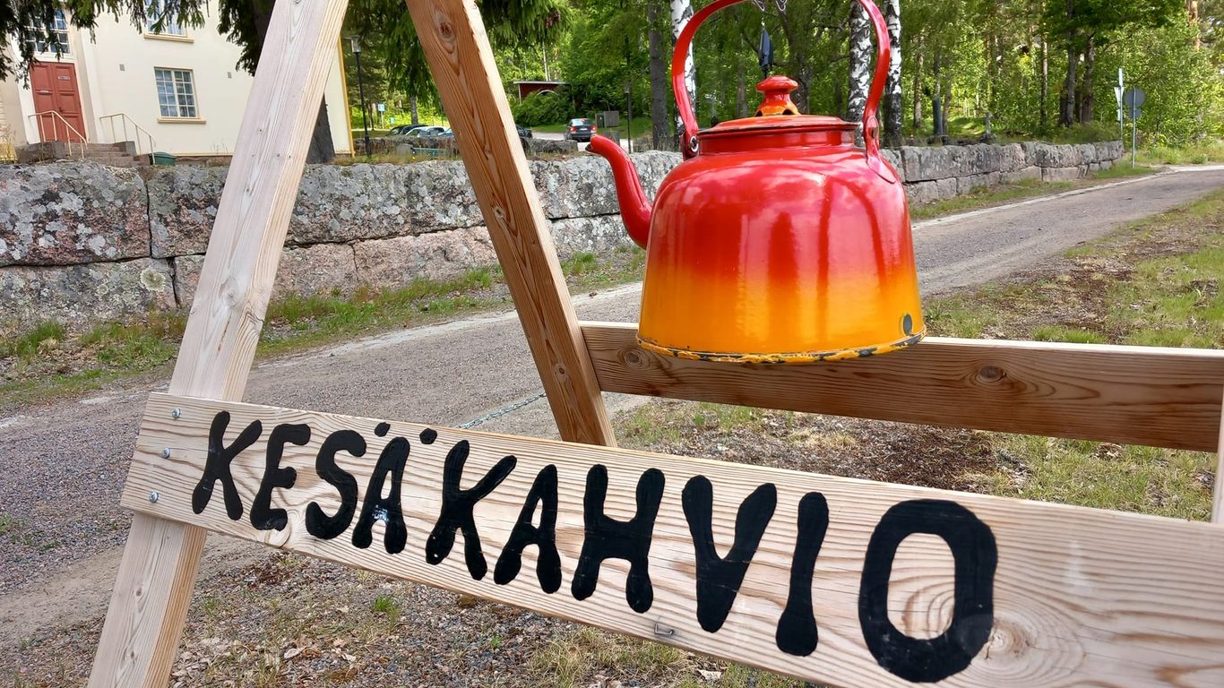 Puna-keltainen kahvipannu telineessä, jossa lukee