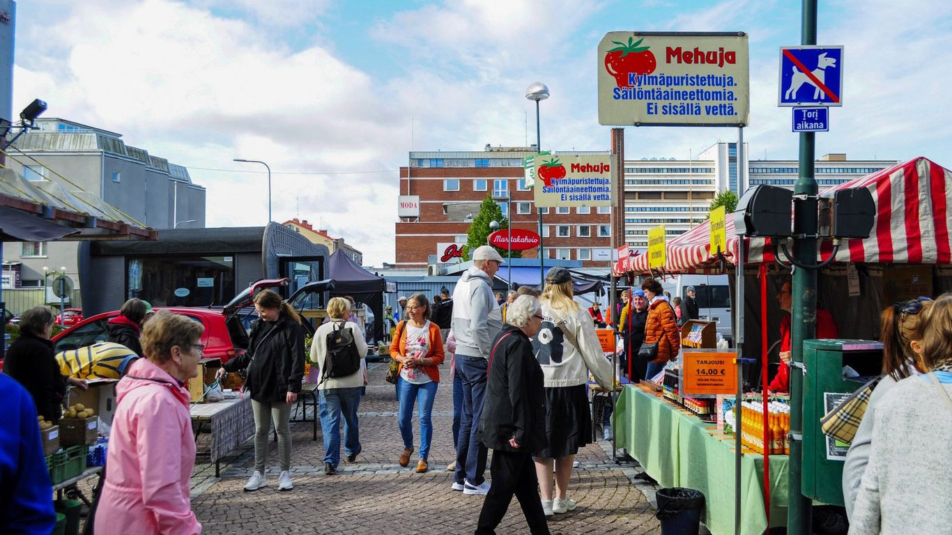 Ihmisiä kauppatorilla tutkimassa myyjien tarjontaa