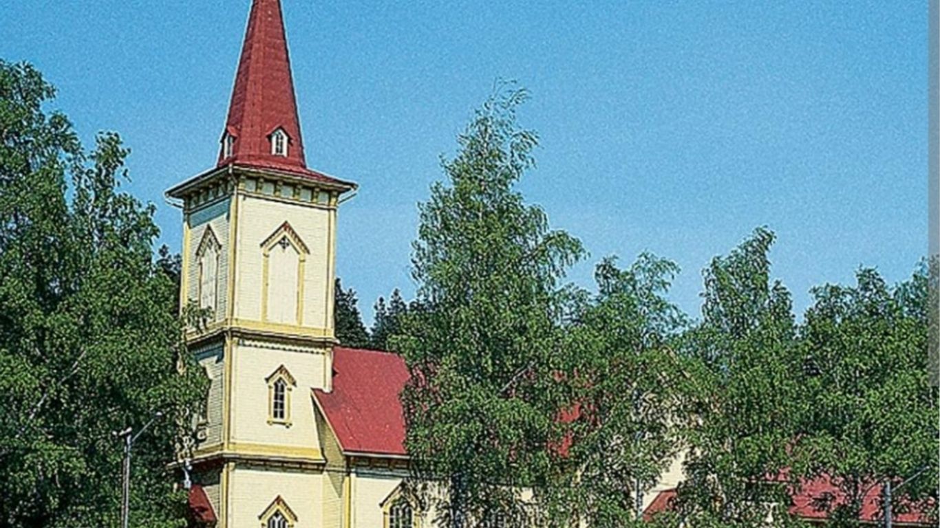 Vaalean kellertävä puinen kirkkorakennus, jossa ko